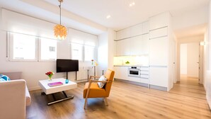 Una sala de estar moderna con un sofá, una mesa de centro, un televisor y un comedor con cocina.