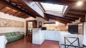 A cozy kitchen with a skylight, white cabinets, and a green sofa.
