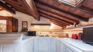A kitchen with white cabinetry, a tiled backsplash, and wooden beams on the ceiling.