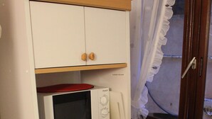 A kitchen with white cabinets, a microwave, and a coffee maker. - studio - Bonifacio (Bonifacio)