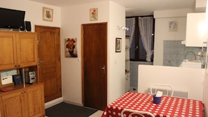 A room with a wooden cabinet, a red polka dot table, a door, and a small table with a blue object. - studio - Bonifacio (Bonifacio)