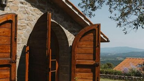 A stone building with wooden doors and a view of the countryside. - Poggio Corsucci - "The Hut" - Stone house in the heart of Tuscany with pool (Loro Ciuffenna (Province of Arezzo))