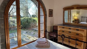 A bedroom with a large arched window, a wooden dresser, and a bed with folded towels. - Poggio Corsucci - "The Hut" - Stone house in the heart of Tuscany with pool (Loro Ciuffenna (Province of Arezzo))
