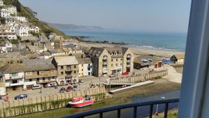 A coastal town with buildings along the waterfront, a red boat docked at the pier, and a clear view of the sea. - Lovely Flat In West Looe With Spectacular Sea & Harbour Views - Non Smokers Only (Looe)