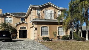 A two-story house with a driveway, a garage, and a well-maintained lawn. - 🏡 7 Bed,7 Bath | Large pool & H/Tub | Large Smart TVs & Sonos every Room I WiFi (Davenport)