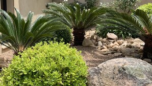 A building with a beige facade, a tiled roof, and a garden with green shrubs and rocks. - Villa with breathtaking views of Pinarello bay and beach (Zonza)