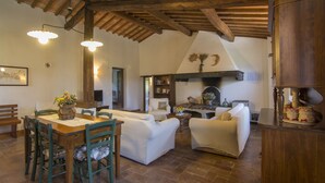 A spacious living area with a wooden ceiling, a dining table with chairs, and a sofa set. - Chianti villa, with private swimming pool! Air conditioning, ULTRA-FAST Wi-Fi (Greve in Chianti)