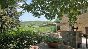 A stone building with a pergola, outdoor seating, and a view of a forested hillside. - Chianti villa, with private swimming pool! Air conditioning, ULTRA-FAST Wi-Fi (Greve in Chianti)