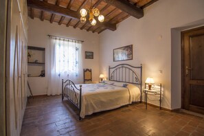 A bedroom with a bed, bedside tables, a chandelier, and a wooden door. - Chianti villa, with private swimming pool! Air conditioning, ULTRA-FAST Wi-Fi (Greve in Chianti)