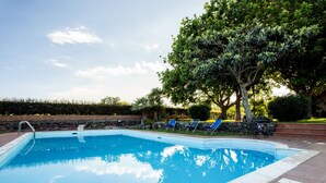 A rectangular swimming pool with a tiled edge, surrounded by a brick patio.
