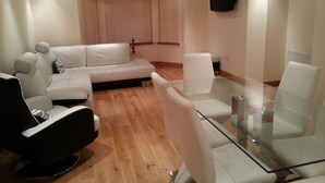 Un salon moderne avec un canapé, une table basse en verre et un téléviseur fixé au mur.
