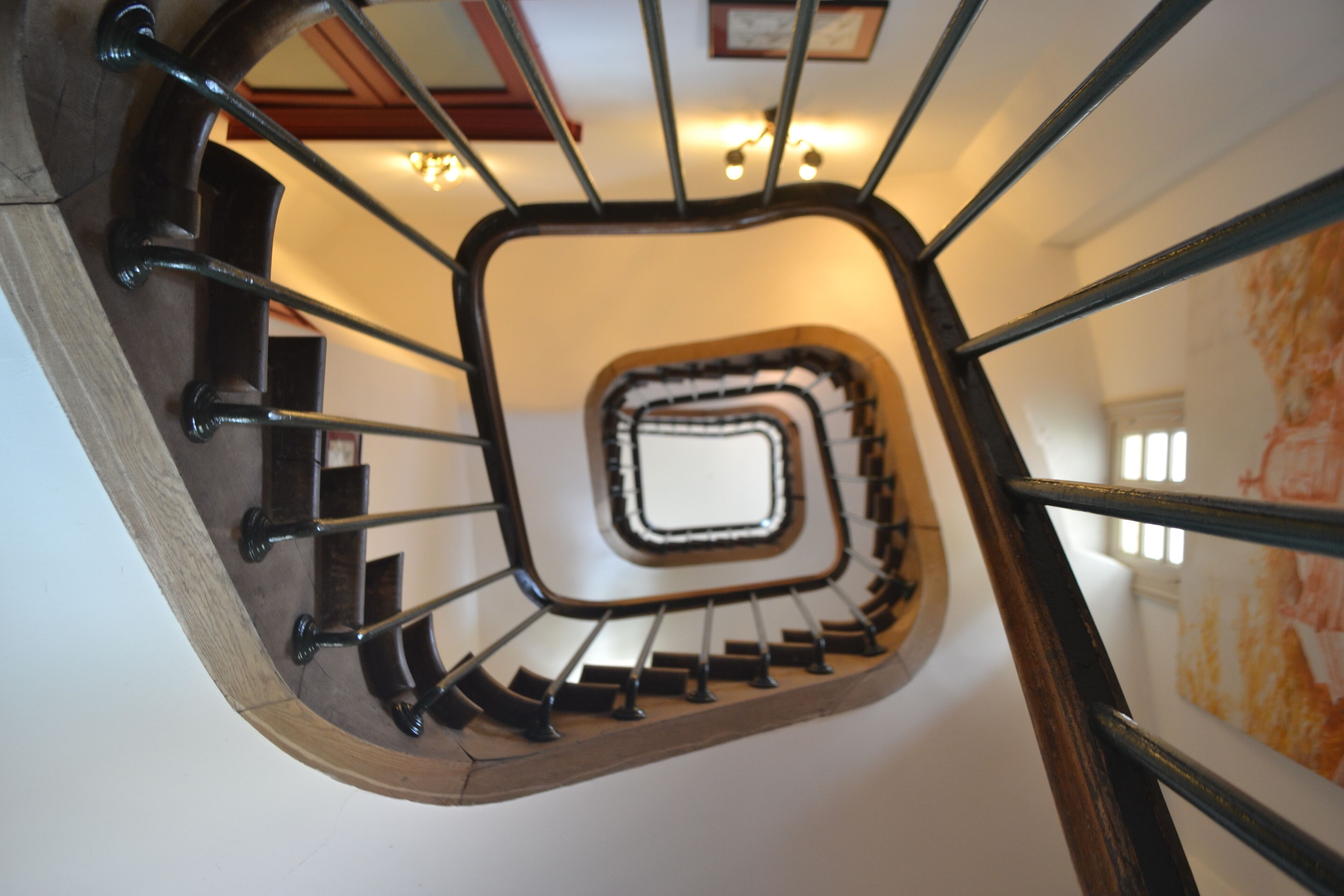 Un escalier en colimaçon doté d’une plateforme centrale carrée et de rampes en métal.