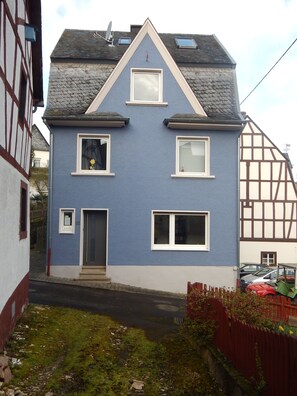 A two-story house with a gabled roof, multiple windows, and a small front porch.