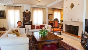Amplia sala de estar con chimenea, sofás blancos, una mesa de centro de madera y un espejo grande.