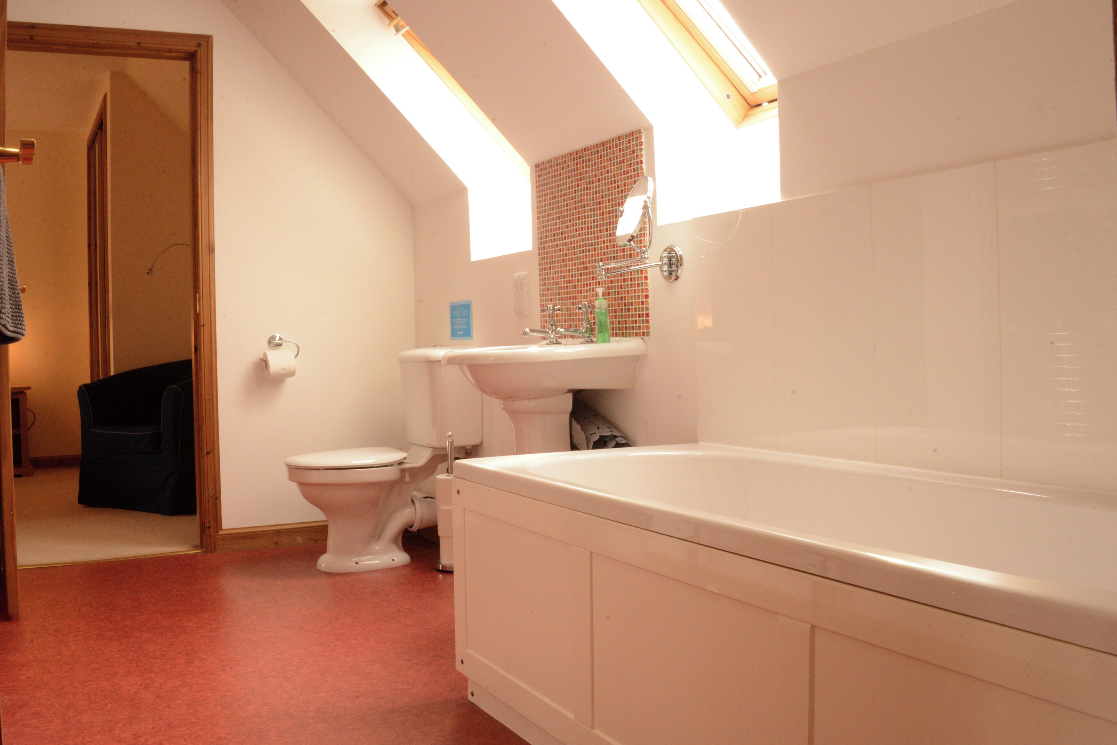 A bathroom with a skylight, a toilet, a sink, and a bathtub.
