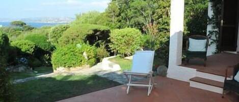 Une terrasse avec vue sur la mer, entourée de verdure et agrémentée d’une chaise.