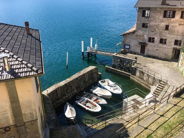A harbor with boats docked, a bridge, and a building with a stone facade.