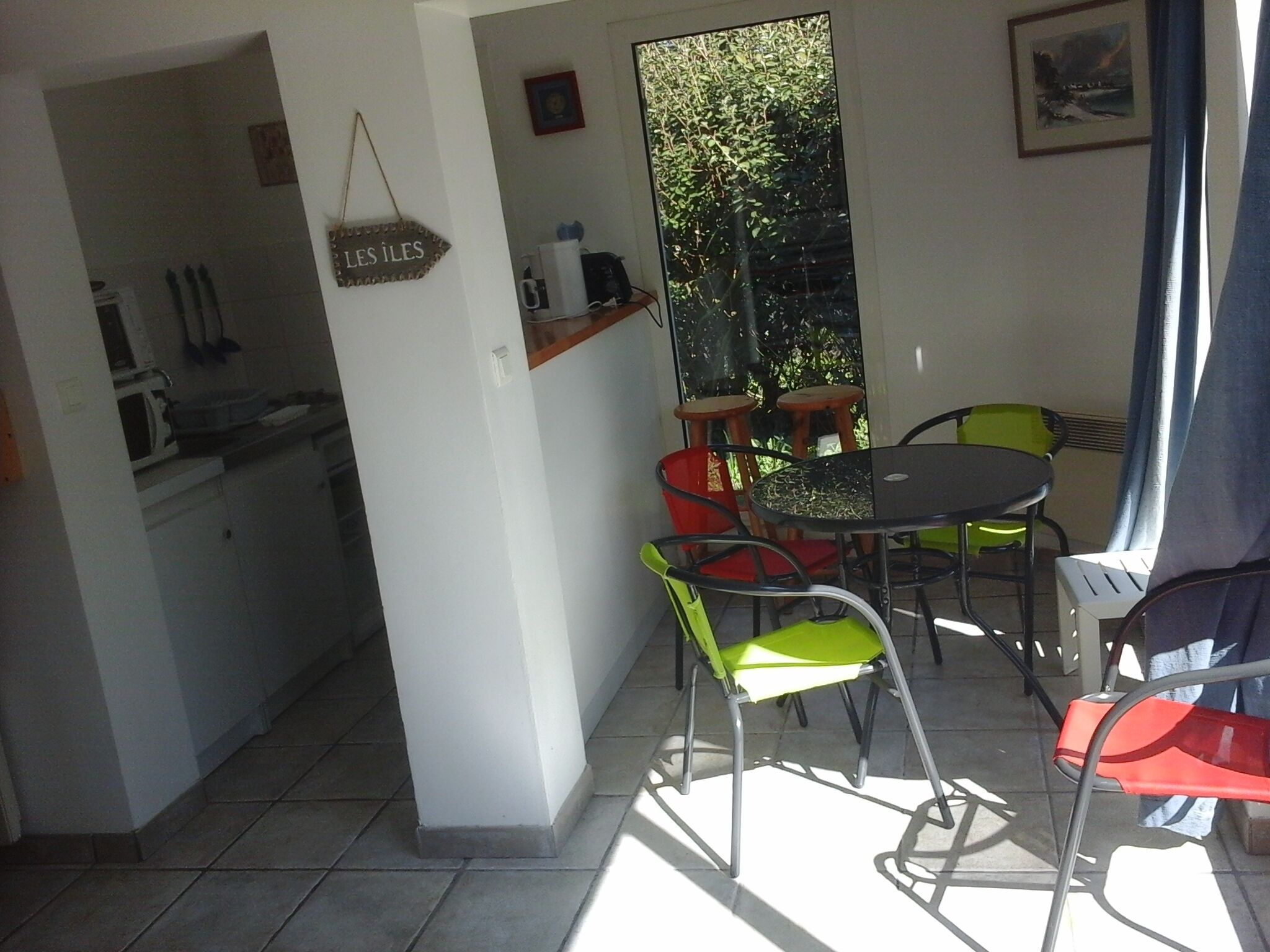 Un pequeño comedor con una mesa y sillas, una cocina con microondas y utensilios, y una ventana con vistas a zonas verdes.