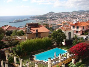 Zona residencial con piscina, vistas al mar y un paisaje urbano montañoso al fondo.