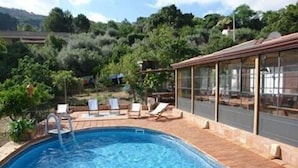 A swimming pool with lounge chairs and a glass-enclosed patio area. - Very nice villa with pool with stunning views in Cefalù  (Cefalu)