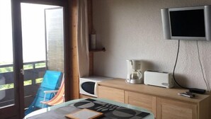 A room with a table, chairs, a television, a coffee maker, and a view of the outside. - Apartment/ flat - Thollon les memises (Thollon-Les-Mémises)