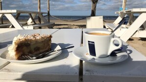 Una mesa en la playa con una porción de pastel y una taza de café.