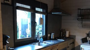 Una cocina con armarios de madera, un lavamanos y una ventana con vistas a un jardín.