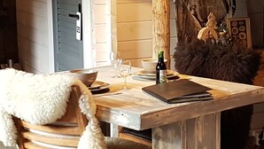 Un comedor con una mesa de madera, sillas y un plaid blanco mullido.
