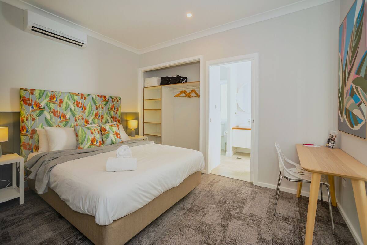 Ein Hotelzimmer mit Bett, Schreibtisch, Stuhl, Kleiderschrank und Klimaanlage.