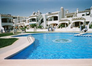 A swimming pool surrounded by multi-story buildings with balconies and a clear sky. - Large Bright Apartment (Non Smoking). 100 Mb wifi (sleeps 4 plus pull out bed). (Orihuela)