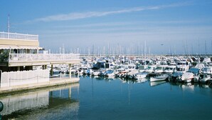 Uma marina com vários barcos atracados, um cais com cerca branca e um edifício com varanda.