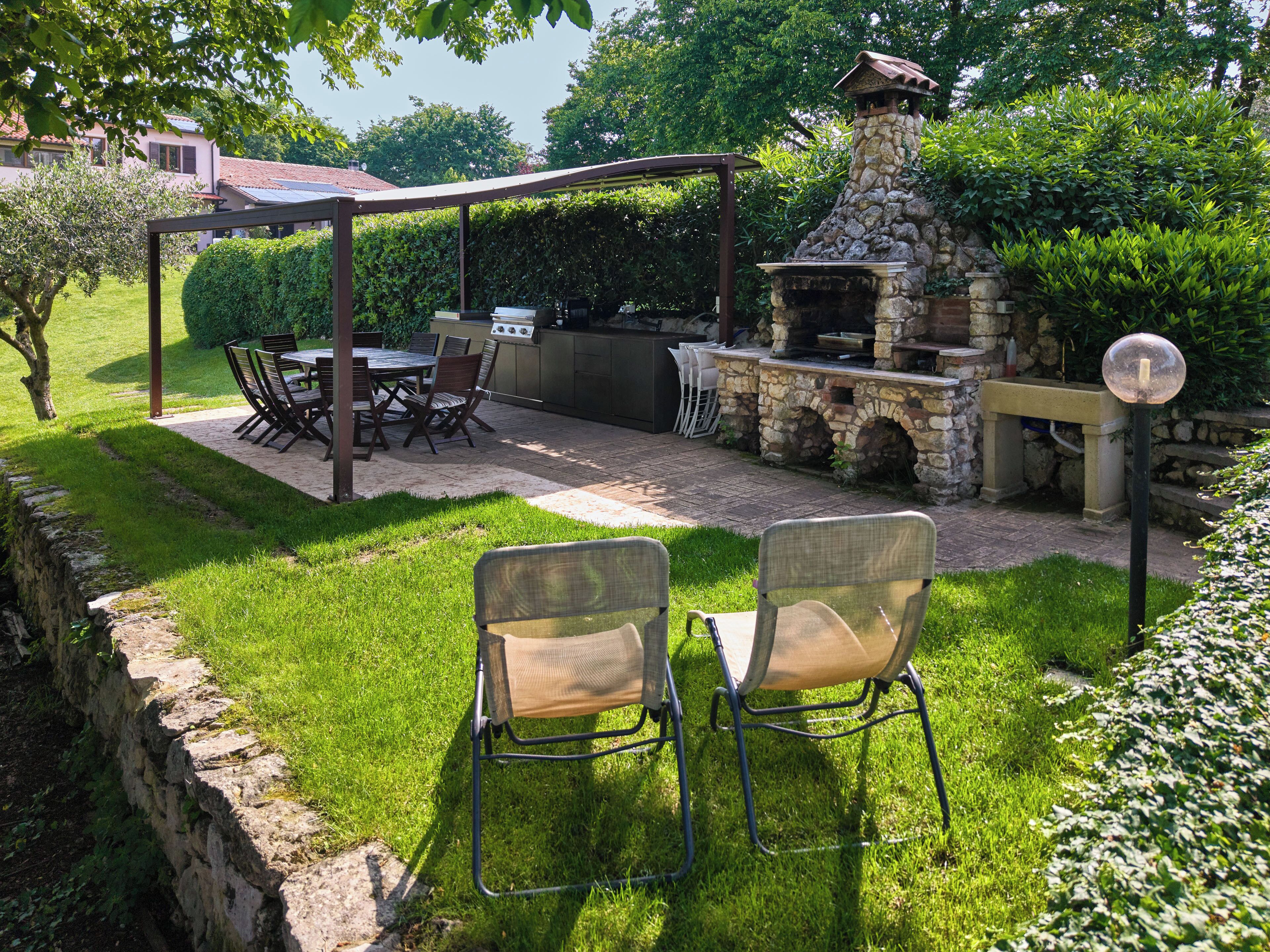 An outdoor patio with a stone fireplace, a grill, and a pergola.