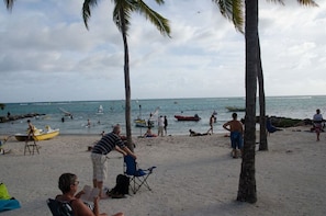 Une plage avec des gens, des bateaux et des palmiers.
