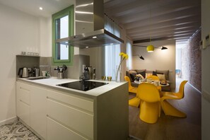 Et moderne køkken med en central ø, et spiseområde med gule stole og en murstensvæg i baggrunden.