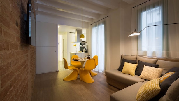 Moderni olohuone, jossa on sohva, keltaiset tuolit ja ruokailutila.