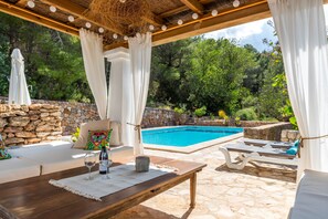 An outdoor seating area with a pool, stone walls, and greenery. - Can Xicu d´es Falcóns (Ibiza)