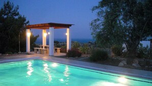 Una piscina amb una pèrgola i vista al mar.