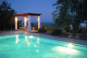 Une piscine dotée d’une pergola et offrant une vue sur la mer.