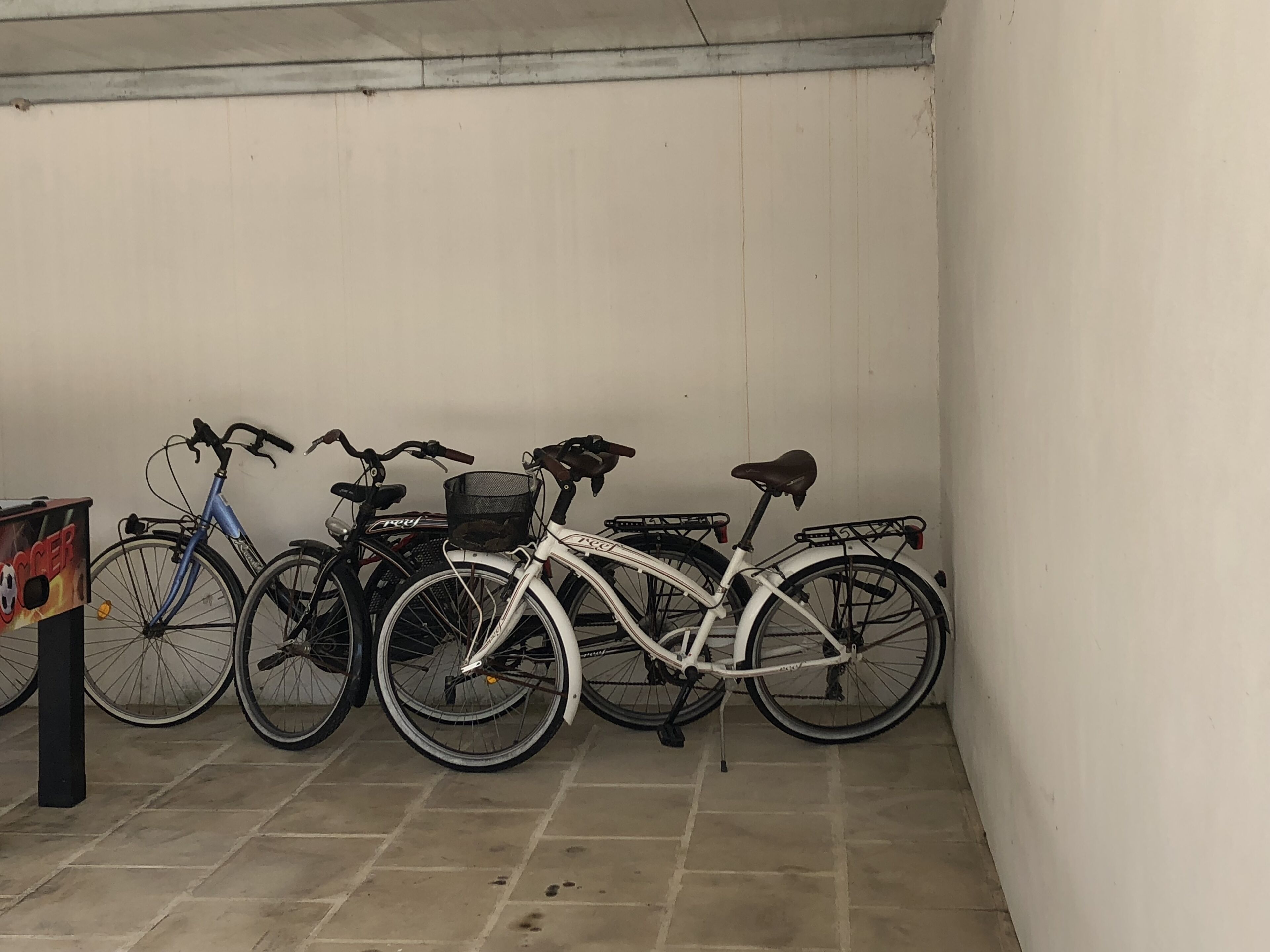 Une rangée de vélos est garée contre un mur dans une pièce carrelée.