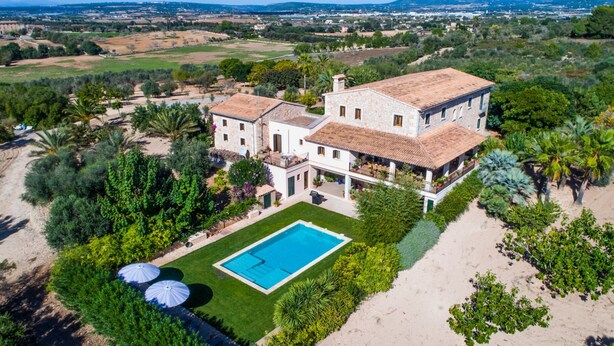 Une vaste villa en pierre dotée d’une piscine, entourée d’une végétation luxuriante et offrant un paysage méditerranéen.