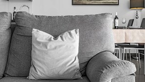 A grey sofa with a single white pillow and a matching throw pillow. - A&M House - Luxury Holidays Home (Arco da Calheta)