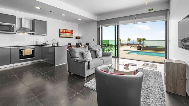 A modern apartment with a kitchen, living area, and a balcony with a pool. - A&M House - Luxury Holidays Home (Arco da Calheta)