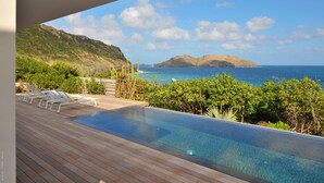 Une piscine avec des chaises longues et vue sur l’océan.