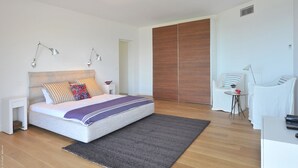 Une chambre moderne comprenant un lit, des tables de chevet, un bureau et une armoire.