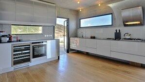 Une cuisine moderne dotée d’appareils électroménagers intégrés, d’une grande fenêtre et offrant une vue sur l’extérieur.