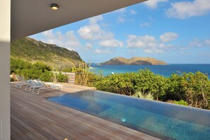 Ein Pool mit Liegestühlen und Blick aufs Meer.