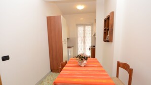 A narrow hallway leading to a dining area with a table set for four, a wooden cabinet, and a small kitchen visible in the background. - Cosy apartment, near Metro A, S. Pietro and the downtown (Roma)