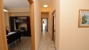 A hallway with a dining area, a TV, and a painting on the wall. - Cosy apartment, near Metro A, S. Pietro and the downtown (Roma)