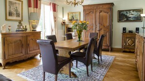 A dining room with a wooden table, chairs, a chandelier, and a large cabinet.