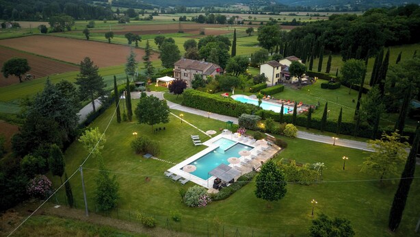 A large, rectangular swimming pool surrounded by a well-maintained lawn and a few lounge chairs. - La Colonica 18, Emma Villas (Citerna)